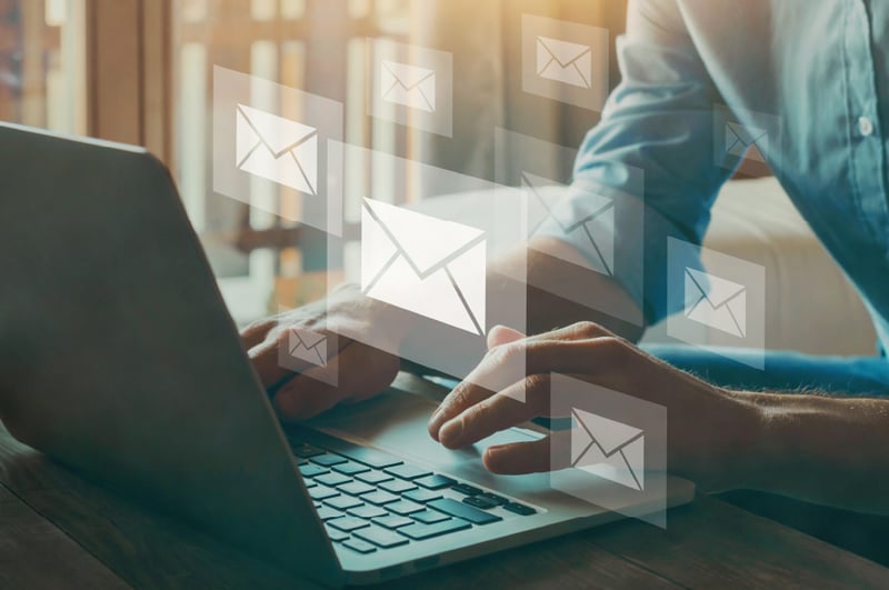 Person typing on laptop, envelope icons in the foreground