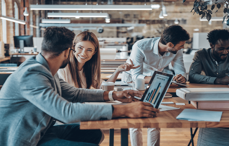 Four smiling coworkers sitting at table