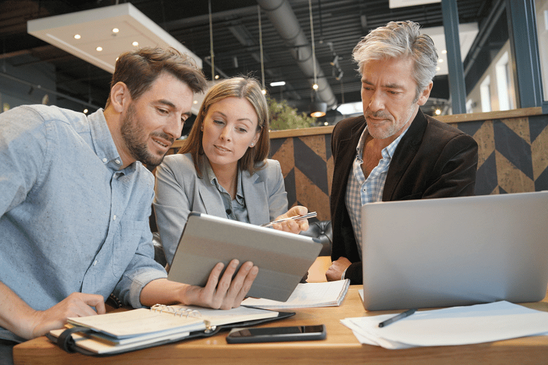 Three people talking and looking at a tablet