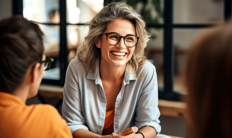 Smiling woman looking at someone opposite out of photo, blong, wearing glasses